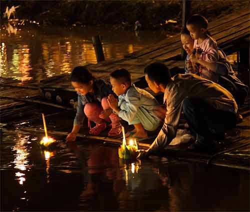 Une famille thaie depose un krathong dans la rivière a Chiang Mai